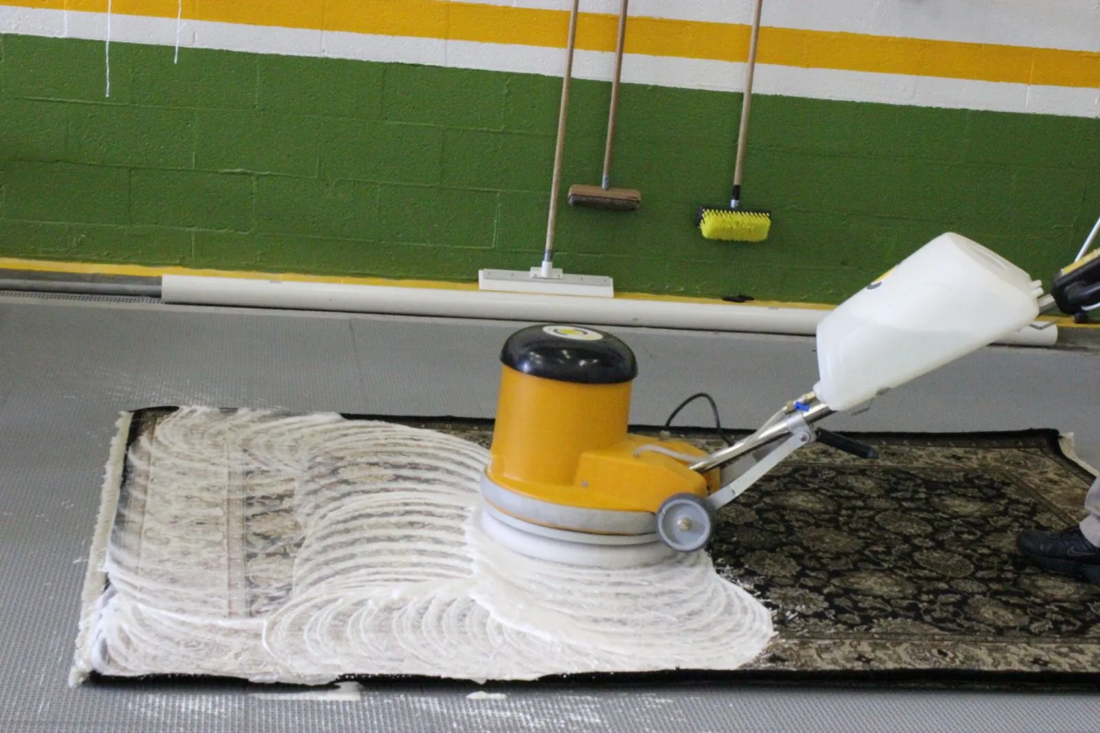 Rug being washed with a gentle rotary brush and pH shampoo